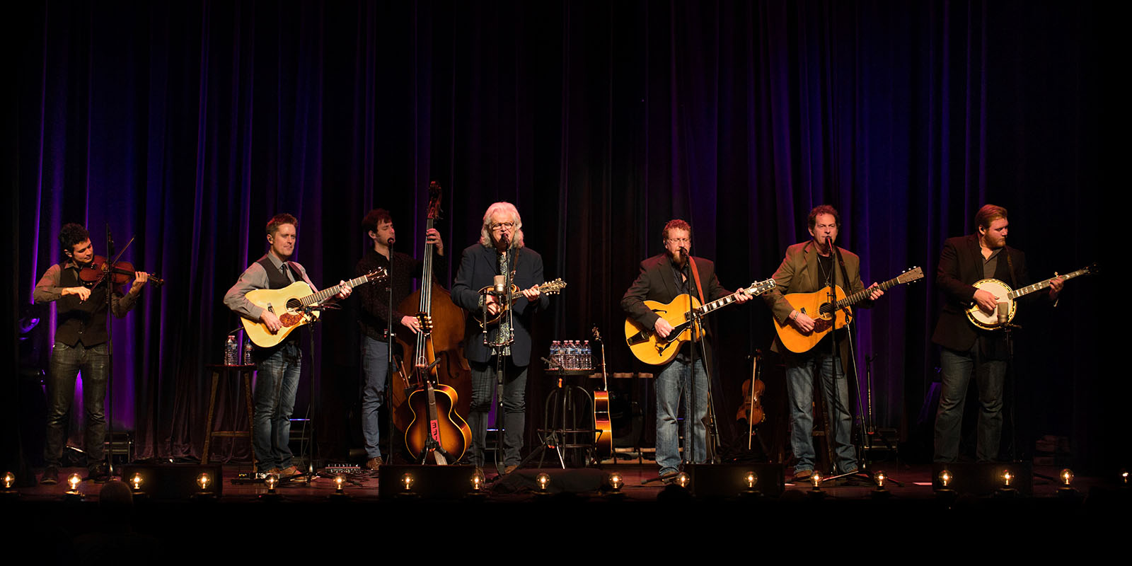 Ricky Skaggs and Kentucky Thunder with guitars as they perform on stage.