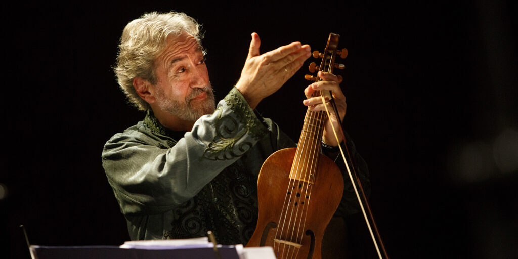 A man holds a string instrument and holds his arm upwards.