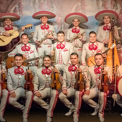 Men in traditional Mexican mariachi clothing and hats hold violins and guitars