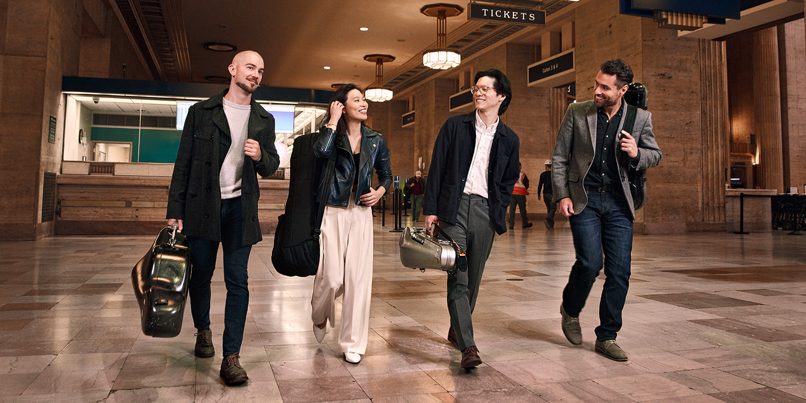 Four musicians walk in a train station.