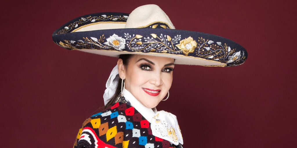 A woman wears a gold and silver sombrero and a colorful shawl.