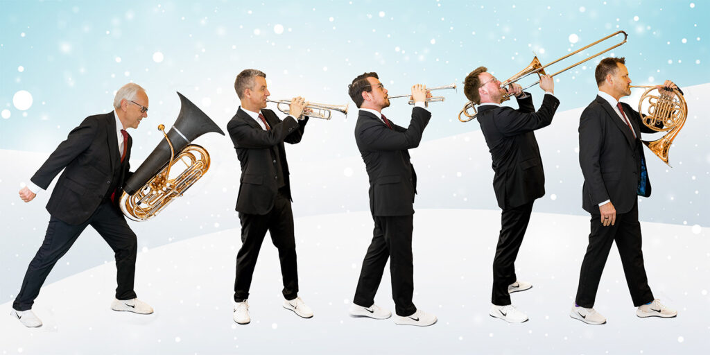 Five men in a dark suits and white sneakers play brass instruments in front of a snowy backdrop.