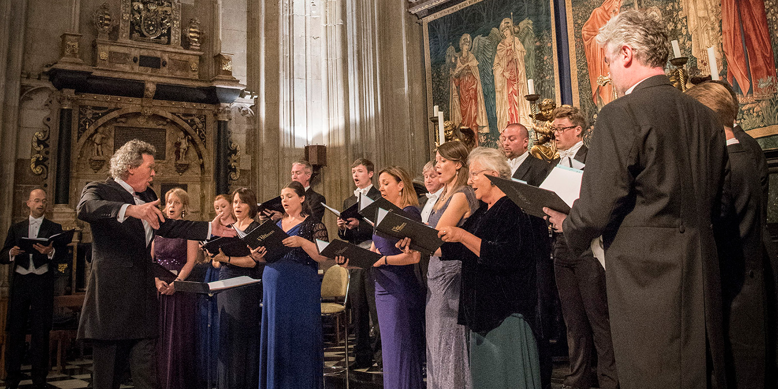 A man conducts a choir singing in an old cathedral.