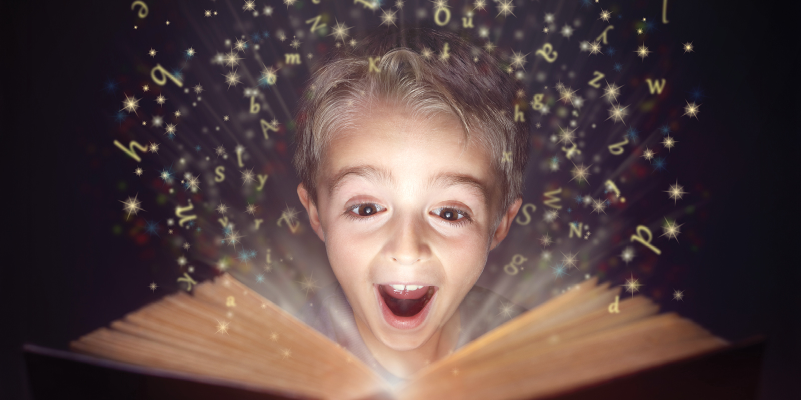 Letters and stars pour out of a book being read by a young boy.